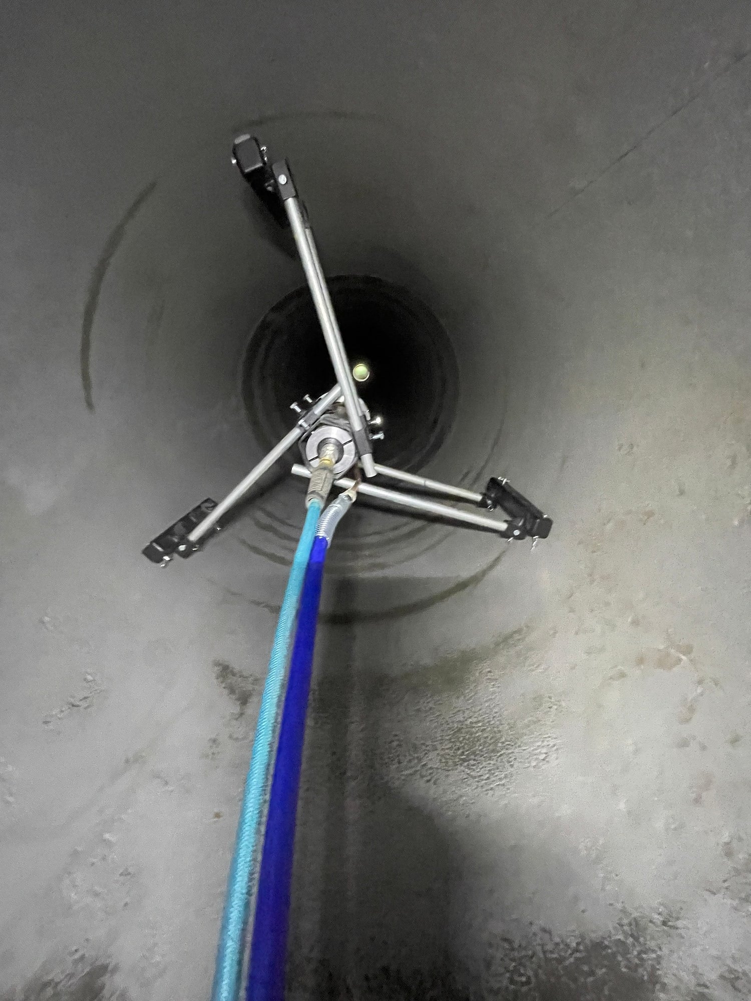 A centrifugal spray head on a lance inside a pipe, applying a new interior lining